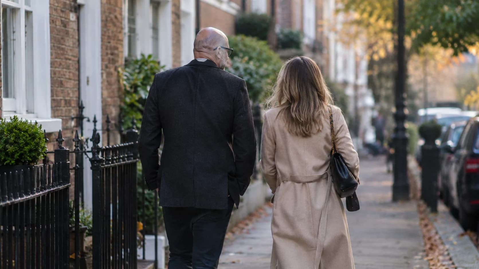 Scott Galloway and his wife walking together along a residential street in an autumn setting.